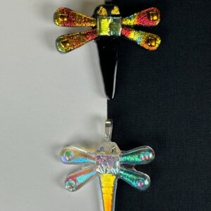 wo dragonfly dichroic glass pendants displaying color-shifting wings from gold to red, arranged on black and white background