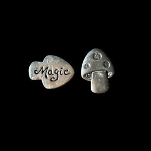 Two silver pewter pieces, one engraved with 'Magic' and the other shaped like a mushroom, displayed side by side on a black background