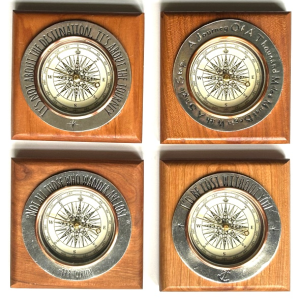 Set of four decorative wooden compasses featuring inspirational travel quotes engraved around the faces, ideal for adventure and journey-themed home décor