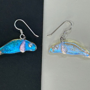 Handmade dichroic glass manatee earrings with silver hooks on black and white background showing color shifting finish